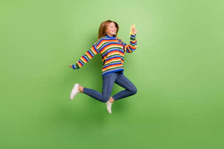 Full length body size view of attractive cheerful funny girl jumping using device app isolated over...