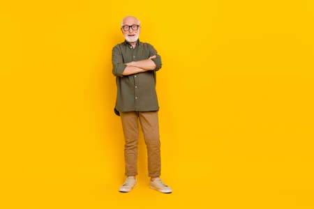 Full body photo of positive aged man folded arms have good mood isolated on yellow color backgroundの写真素材