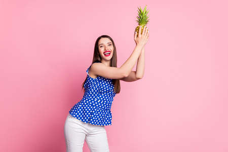 Portrait of attractive cheerful girl holding ananas dancing having fun isolated over pink pastel color backgroundの写真素材