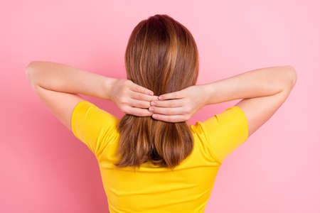 Back rear side photo of young school girl make hairdo haircare lotion incognito isolated over pink color backgroundの写真素材