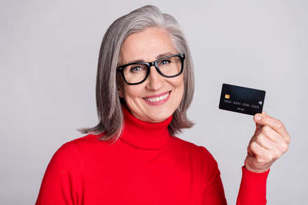 Photo of senior woman happy positive smile hold credit card shop buy customer isolated over grey color backgroundの写真素材