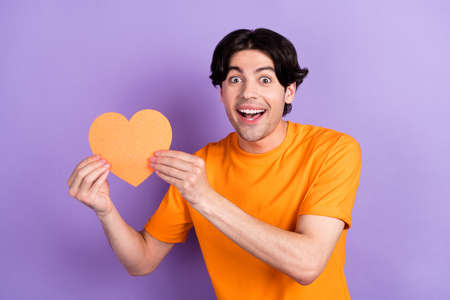 Photo of positive cheerful happy young amazed man hold hands heart shape smile isolated on purple color backgroundの写真素材