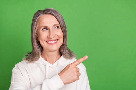 Photo of pretty sweet old woman dressed white sweatshirt smiling looking pointing empty space...