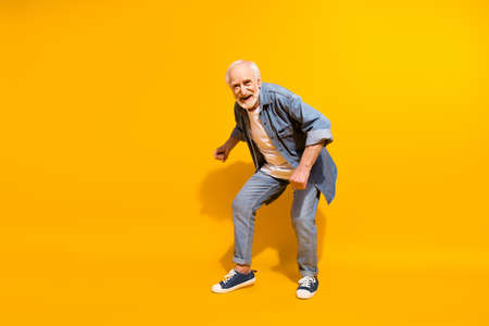 Full length body size of cool grandfather dancing feeling young wearing stylish outfit isolated on vivid yellow color backgroundの写真素材