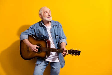 Photo portrait of grandpa playing guitar looking blank space isolated vibrant yellow color...