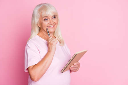 Photo portrait of dreamy woman touching cheek face with pen holding notepad isolated on pastel pink...