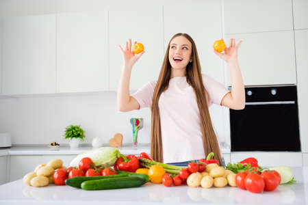 Portrait of attractive cheerful long-haired girl cooking fresh dinner having fun at home light white kitchen house indoorsの写真素材