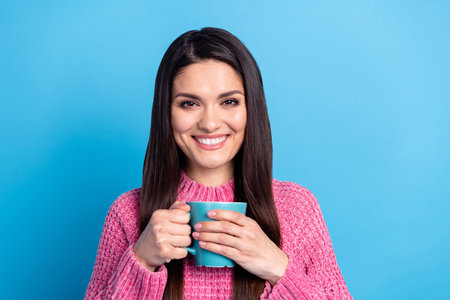 Photo of adorable sweet mature woman wear pink pullover enjoying coffee holding cup isolated blue color backgroundの写真素材