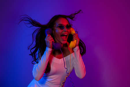Photo of hooray millennial brunette lady talk two telephones wearing white dress spectacles isolated...