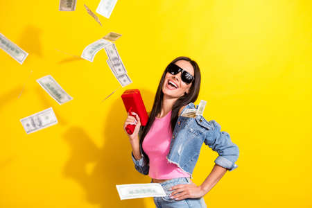 Portrait of attractive trendy cheerful girl shooting atm 100 usd blow flow having fun isolated over...