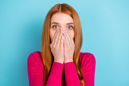 Portrait of attractive worried red-haired girl closing face oops isolated over vivid blue color backgroundの写真素材
