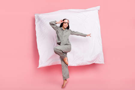 Full length photo of funny charming lady sleepwear mask jumping high smiling isolated pink color backgroundの写真素材