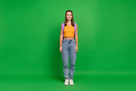 Full size photo of nice millennial brunette lady stand wear bag top jeans shoes isolated on green color backgroundの写真素材