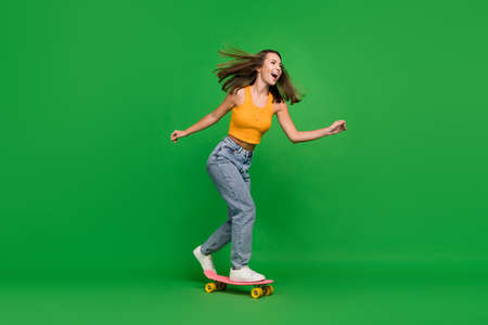 Full length photo of young impressed brunette lady go wear top jeans shoes isolated on green...