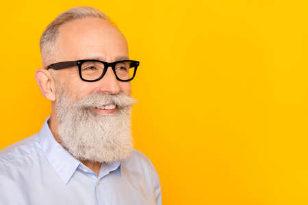 Photo of dreamy happy old charming man look empty space wear glasses isolated on yellow color backgroundの写真素材