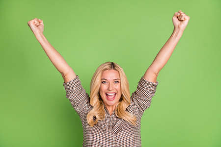 Photo portrait of blonde woman happy overjoyed gesturing like winner isolated bright green color backgroundの写真素材