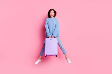 Full length body size view of attractive cheerful crazy girl jumping holding case station isolated over pink pastel color backgroundの写真素材