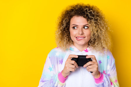 Portrait of attractive cheery sly wavy-haired girl in pajama playing console copy space isolated...