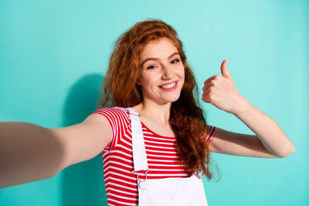 Self-portrait of attractive cheerful girl showing thumbup ad cool trust perfect isolated vivid blue...