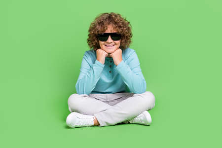 Portrait of attractive cheerful guy sitting resting wearing specs isolated over vivid green color backgroundの写真素材