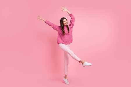 Full size photo of brunette optimistic girl dance wear pink sweater pants sneakers isolated on crimson color backgroundの写真素材