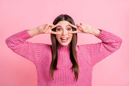 Portrait of brunette optimistic girl show v-sign wear pink sweater isolated on crimson color backgroundの写真素材