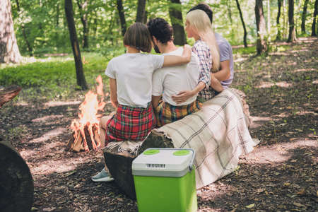 Rear back behind view portrait of attractive four people hugging spending free time in park on fresh air watching fire outdoorsの写真素材