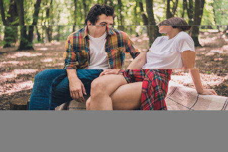 Portrait of attractive cheerful two people traveling exploring wild park sitting on cover spending free time weekend outdoorsの写真素材