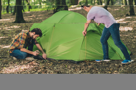 Portrait of attractive busy focused two guys traveling exploring wild park setting tent active lifestyle weekend outdoorsの写真素材