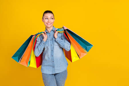 Photo of dreamy happy nice young woman hold sale bags look empty space isolated on yellow color...