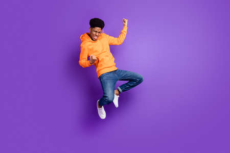 Full length photo of young crazy dark skin man jump up air fists winner celebrate isolated on violet color backgroundの写真素材