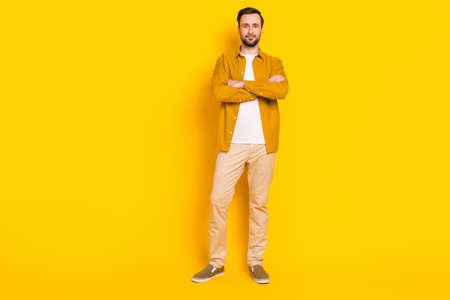 Full length photo of sweet confident young gentleman dressed casual outfit standing hands folded isolated yellow color backgroundの写真素材
