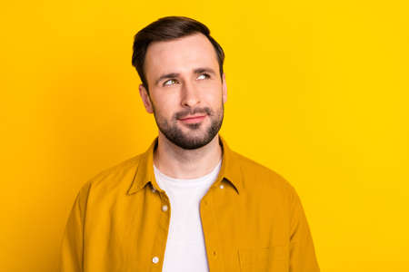 Photo of young handsome man happy positive smile dream think look empty space isolated over yellow...