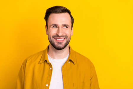 Photo of young cheerful handsome man happy positive toothy smile look empty space isolated over yellow color backgroundの写真素材