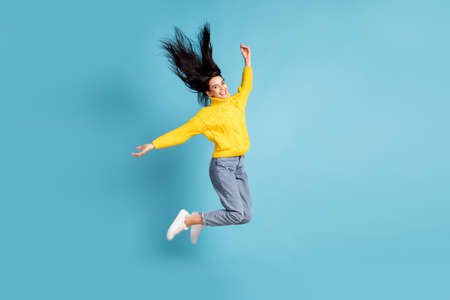 Full length body size side photo of brunette jumping high throwing hair in the air isolated on vivid blue color backgroundの写真素材