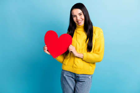 Portrait of attractive cheerful girl holding in hands heart 14 February isolated over bright blue color backgroundの写真素材