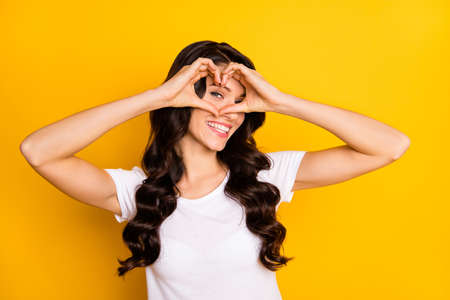 Portrait of attractive cheerful wavy-haired girl showing heart shape sign isolated over bright...