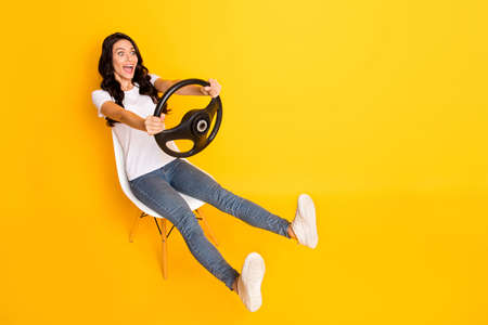 Full size profile side photo of excited girl hold steering wheel sit chair speed isolated on yellow...