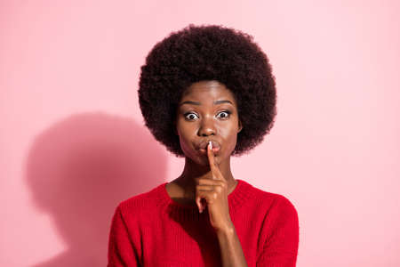 Photo of dark skin lady finger covering mouth lips look camera wear sweater isolated on pink color backgroundの写真素材