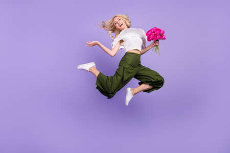 Photo of active lady jump hold bouquet run wear white blouse flared trousers isolated purple color...