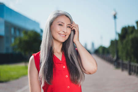 Portrait of attractive cheerful grey-haired woman enjoying spending free spare time weekend breathing fresh air outdoorsの写真素材