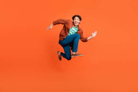 Full size photo of cheerful good mood man running in air traveling wear brown shirt isolated on...