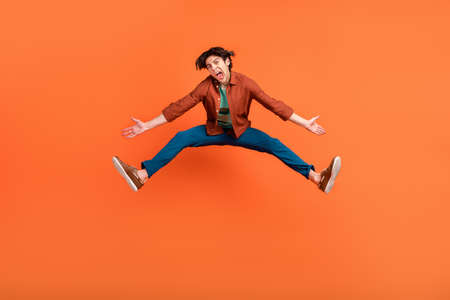 Full size photo of funky funny man jumping unhappy shrug shoulders fooling around isolated on orange color backgroundの写真素材