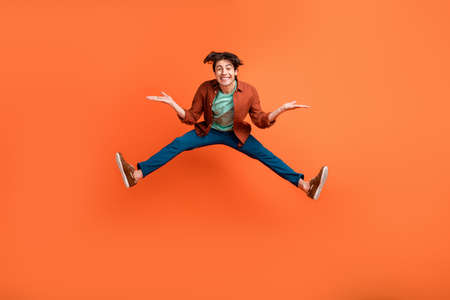 Full size photo of cheerful smiling funky guy jumping fooling around energetic isolated on orange color backgroundの写真素材