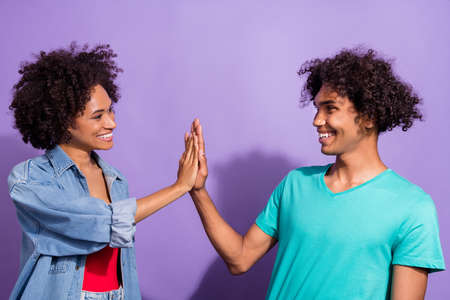 Photo of positive young happy afro american people give high-five teamwork isolated on violet color backgroundの写真素材