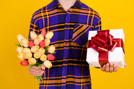 Cropped photo of young guy hold flowers present wear checkered shirt isolated on yellow color...