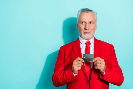 Photo of thoughtful retired man wear red three piece suit holding bank card empty space isolated turquoise color backgroundの写真素材