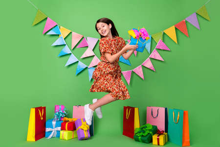Full length body size view of attractive cheery girl jumping having fun decor isolated on bright green color backgroundの写真素材