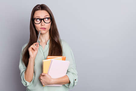 Photo of think brunette student lady look empty space hold books wear blue blouse isolated on grey color backgroundの写真素材