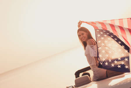 Profile side photo of young girl cabriolet good mood hold american flag journey 4-july citizen outdoorsの写真素材